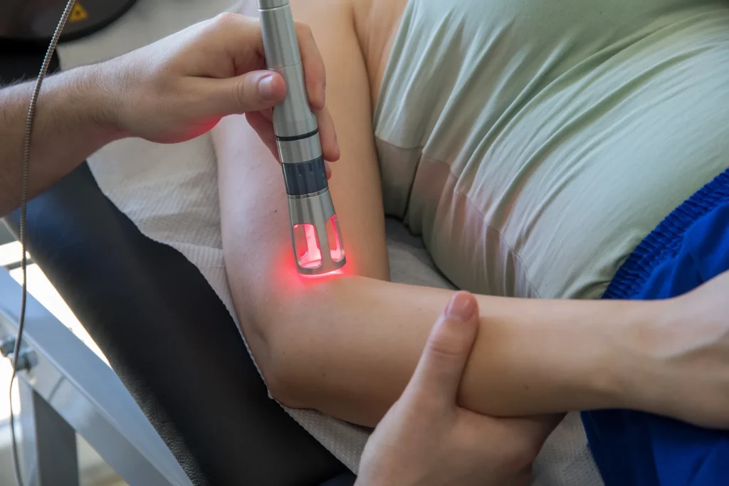 A therapeutic laser handpiece in use during a session in Dumont
