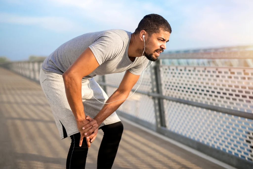A runner stopping to hold a painful knee
